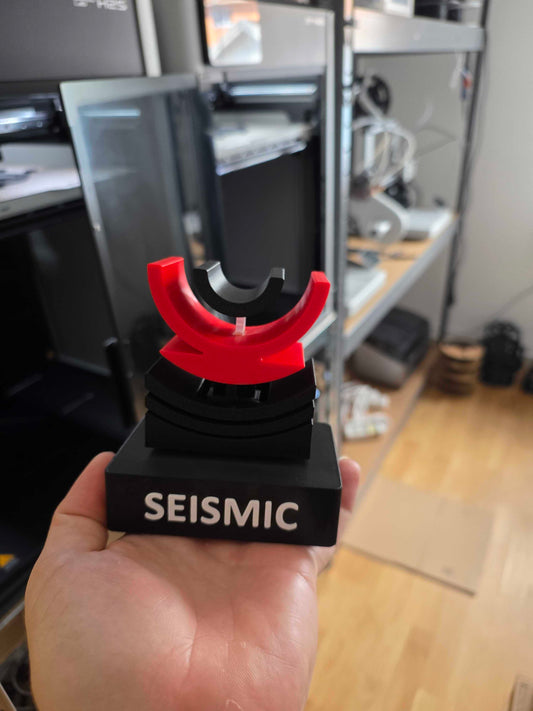 Pokal till Dynapac med svart sockel, relieftext SEISMIC och röd båge på fjädrande topp